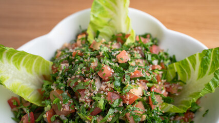 A bowl of delicious fresh Tabbouleh (tabbouli) salad with parsley, mint, tomato, onion, olive oil and lemon juice.