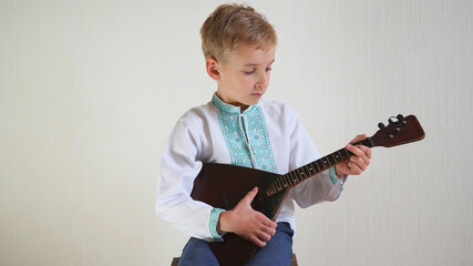 Russian boy in national dress plays the balalaika.