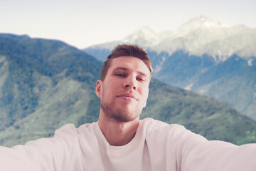 young man hiking the mountain, making a self portrait on the mountain peak