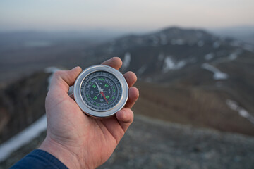 Compass in the hand of a tourist against the background of mountains of nature. Travel, trip, tourism. GPS navigation orienteering, route