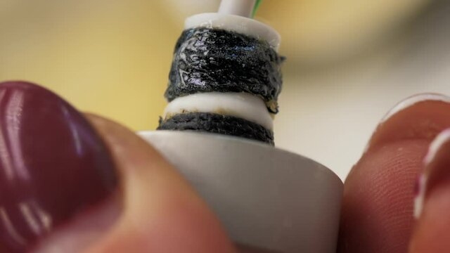 Radio Parts Manufacturing. Small Electronic Details. Close-up of a Female Factory Worker Hands Covering a Piece of Thread with Clear Substance. Using a Tiny Brush. Intricate Manual Work.