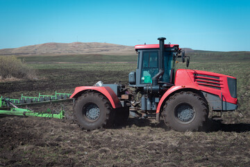 Obraz premium Tractor in the field, works the land.