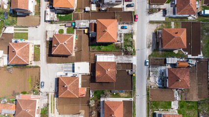 Aerial drone view of residential houses with red roofs and streets with parked cars in town. A view from above on the roof of the houses in city. Cityscape