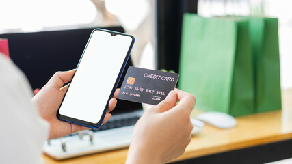 Young women hold credit cards and use laptop computers and mobile telephones to shop online, e-commerce, internet banking, spend money, work from home.