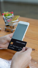 Young women hold credit cards and use laptop computers and mobile telephones to shop online, e-commerce, internet banking, spend money, work from home.