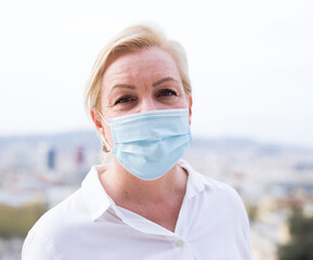 Portrait of mature woman in a protective face mask standing outside museum building