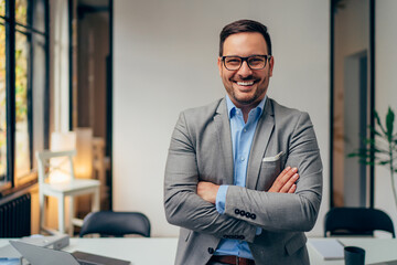 Portrait of young businessman standing in his office with arms crossed
