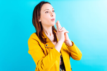 Beautiful young adult woman in yellow jacket blowing her fingers like a gun. weapons concept....