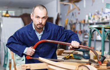 Experienced craftsman repairing antique furniture in workshop using tools