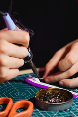 Close up of man with soldering iron working with flex neon near rosin on self-healing cutting mat 