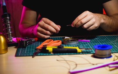 Artisan holding wires near tools and flex neon in workshop 