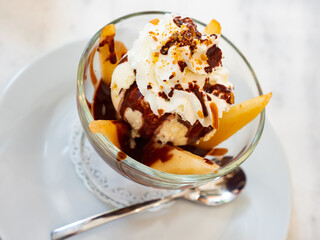 Contrasting French dessert Poire belle Helene of hot poached pears with cold ice cream, whipped cream and chocolate syrup