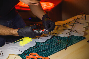 Craftsman cutting wires of neon signboard with cutters on self-healing cutting mat