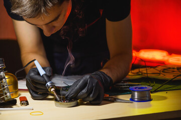 Craftsman with soldering iron and rosin soldering wires for neon signboard 