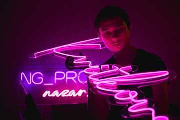 Young designer checking quality of modern neon signboard 