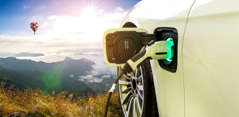 Power supply connect to electric car for add charge to battery. Charging re technology industry transport which are the future of the Automobile with beautiful landscape, Travel challenging concept.