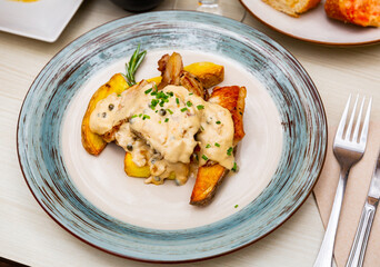 Delicious fried pork escalopes with spicy Roquefort cheese sauce and side dish of potatoes