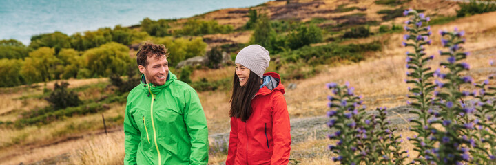 Fototapeta premium New Zealand travel - couple tourists hiking at nature view of Lake Pukaki near Aoraki aka Mount Cook, a famous travel road trip tourist destination. Panoramic banner of young couple hiking in nature