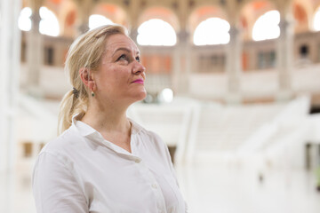 Closeup on attentive elegant senior woman wearing white blouse visiting museum