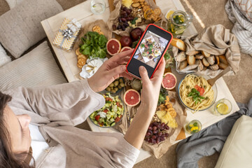 Naklejka na ściany i meble Top view woman photographing dinner table with serving tasty food and drink use smartphone