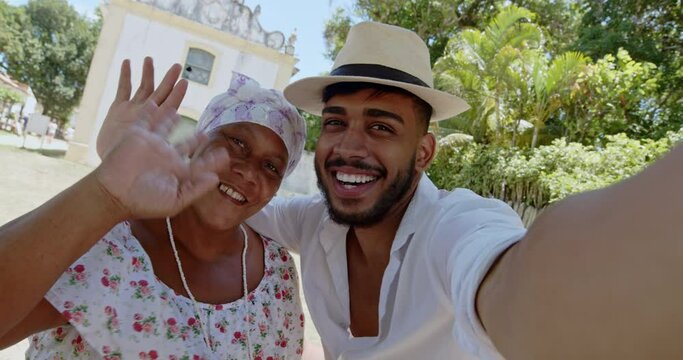 Friendly young Latin American man taking a photos with Bahian in Porto Seguro, Bahia. 6K.