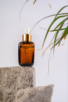 The bottle of Essence is on the pedistal. Lotion on a white background. Cosmetics for skin health. Aromo Oil. Serums with vitamin C. Unisex cosmetics. Mockup. 
