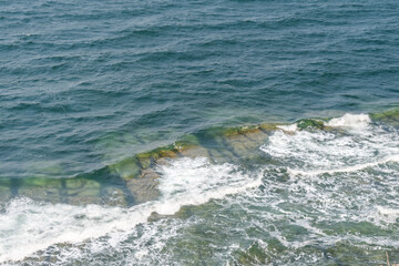 Sea waves crash against rocks and form foam