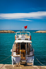 White yacht boat with Turkish flag anchored in the bay of the ancient city of Side, Turkey, back view