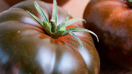 Deliciously vibrant amore tomato on a wooden cutting board. Graded in dark green and dark red...