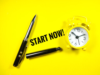 Selective focus of clock and pen with text START NOW on yellow background.Business concept.