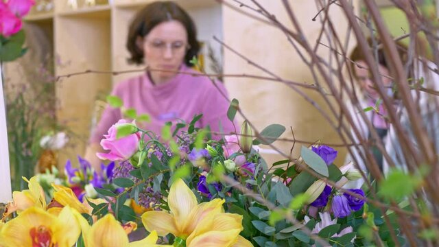 Florist woman works in a greenhouse creates bouquets of flowers before the holiday .Small business.
