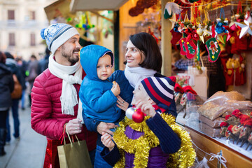 Obraz premium Ordinary parents with kids choosing X-mas decorations in market