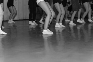 Fototapeta na wymiar legs of little dancers dancing on stage in a row, monochrome