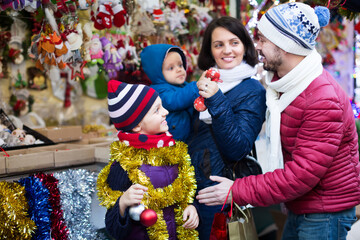 Positive family with children purchasing decoration and souvenirs at Christmas market