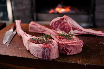 Tomahawk steak on a large wooden cutting board There was a backdrop of a bonfire in the grill.