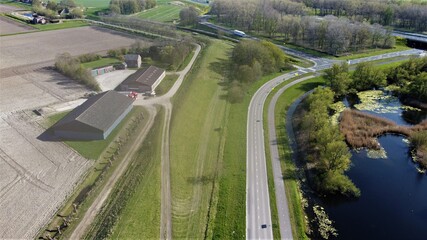 Farm situated on a road in green surroundings. Arable land that has been plowed to cultivate new crops. Aerial view made with drone.