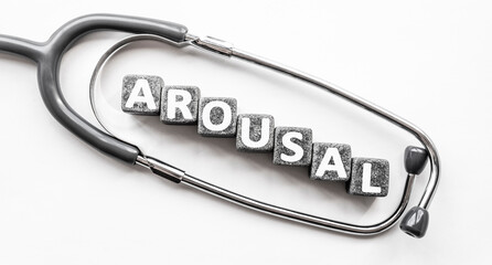 Stone block form word AROUSAL with stethoscope. White background. Medical concept. state of being...