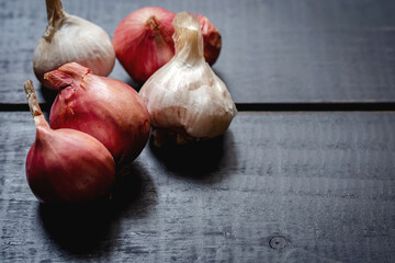 Red onions and garlic on black wooden board.