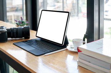 Mockup blank screen tablet with keyboard on wooden counter table in cafe.
