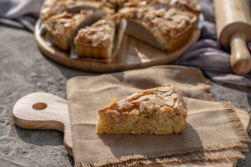 Piece of delicious homemade almond tart on wooden board. - obrazy, fototapety, plakaty
