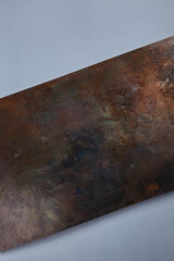 Rusted metal material. Rusty metal plate on textured dark blue table. Old, grunge texture. Top view, flat lay.