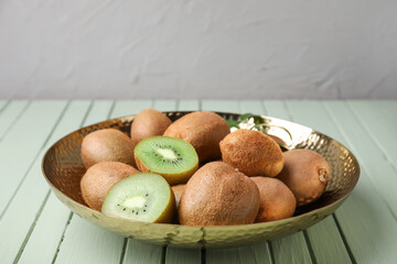Bowl with tasty kiwi on color wooden background