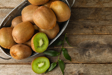 Wicker basket with tasty kiwi on wooden background