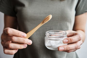 Fototapeta na wymiar Woman holds bamboo toothbrush and soda powder in her hands