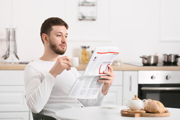 Handsome man reading newspaper in kitchen