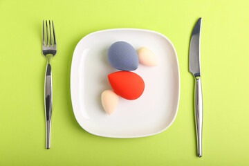 Table setting with makeup sponges on color background