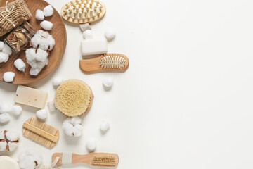 Composition with massage brushes, bath supplies and cotton flowers on white background