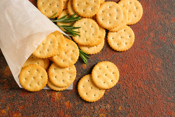 Bag with tasty crackers on grunge background
