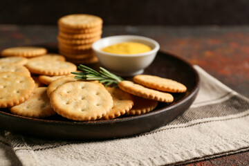 Plate with tasty crackers on table