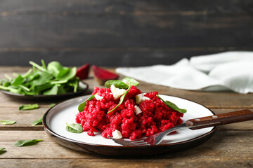 Plate with tasty beet risotto on wooden background